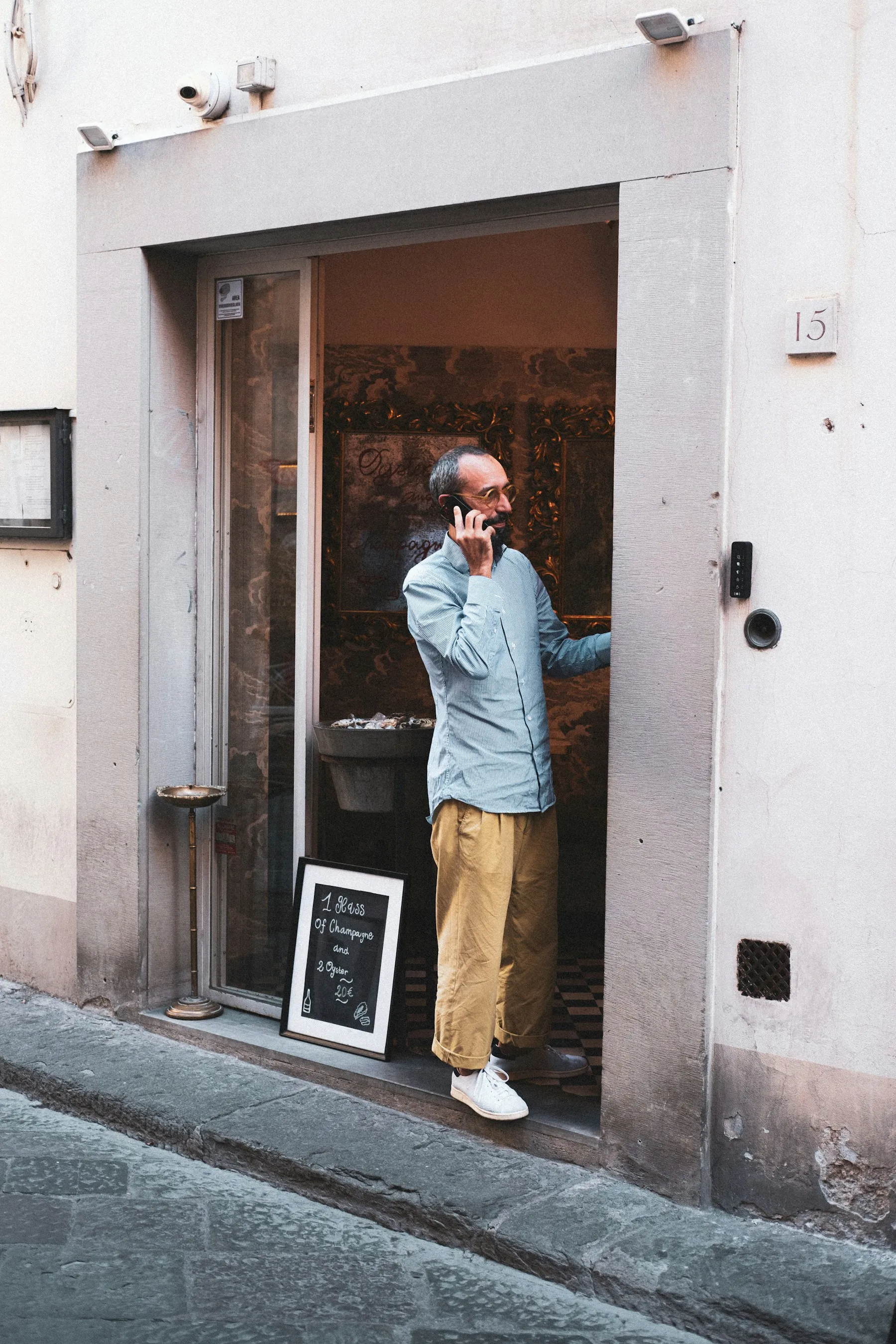 Restaurateur au téléphone sur le pas de la porte de son bistrot